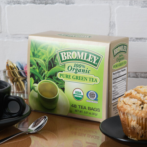 A box of Bromley Organic Green Tea on a table next to a green mug.