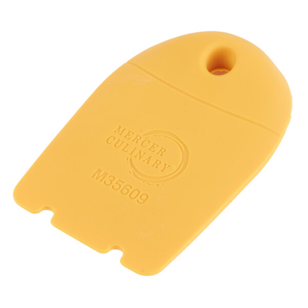A yellow plastic Mercer Culinary horseshoe-shaped plating tool with a hole.