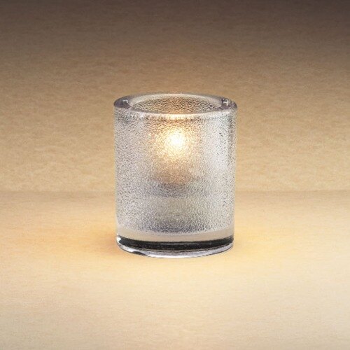 A Sterno clear glass candle holder with a lit candle.