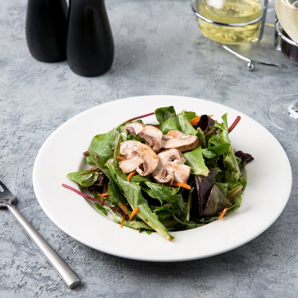 A Libbey white porcelain plate with salad, mushrooms, and carrots.