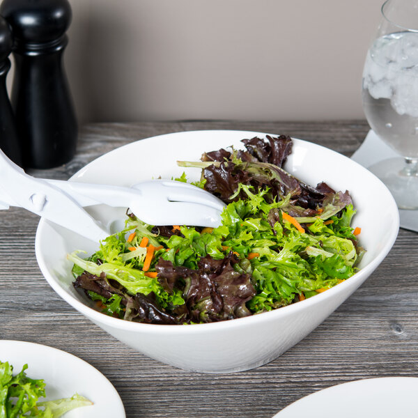 A Libbey round white porcelain bowl filled with salad on a table.