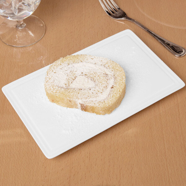 A piece of cake on a Libbey rectangular white porcelain tray next to a fork.