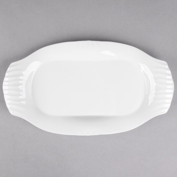 A white Libbey porcelain platter with a curved edge on a gray surface.