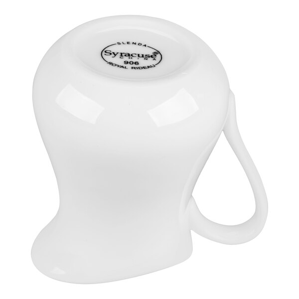 A white porcelain creamer with a handle, shown upside down to display the manufacturer's mark on the bottom.