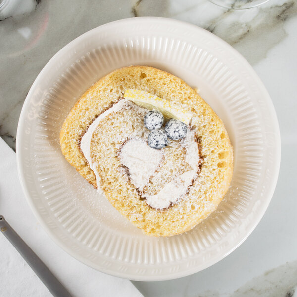 A Tuxton Hampshire eggshell embossed china bread and butter plate with a piece of cake.