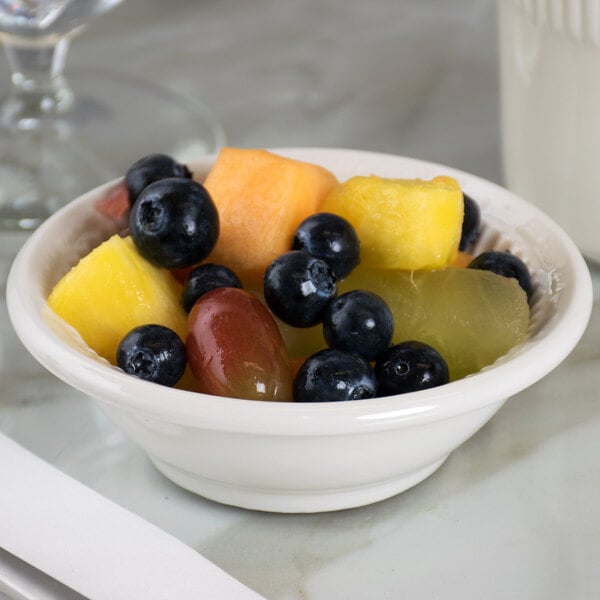 A Tuxton Hampshire eggshell embossed china fruit dish filled with fruit on a table.