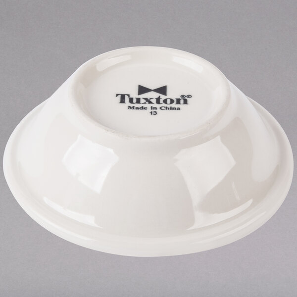 A white Tuxton China bowl with black embossed text.