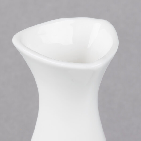 A close up of a white vase with a curved shape.