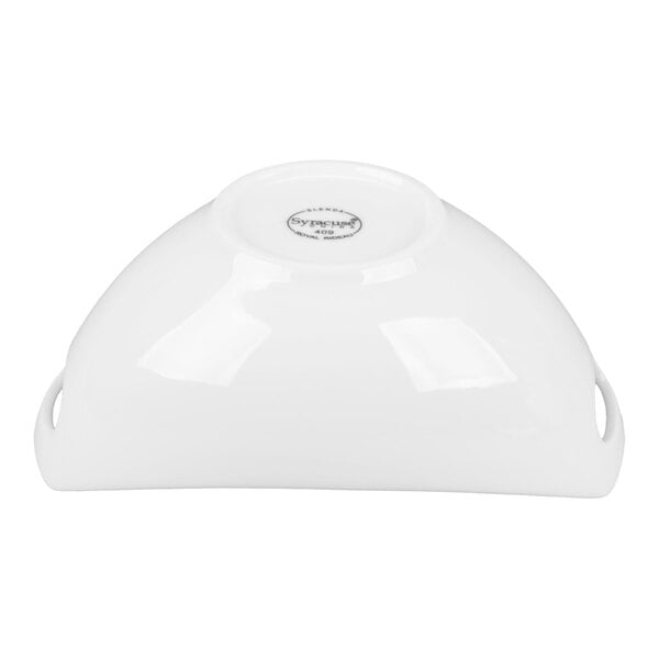 A white porcelain bowl with handles is shown upside down, displaying its smooth, glossy surface and a manufacturer's mark on the base.