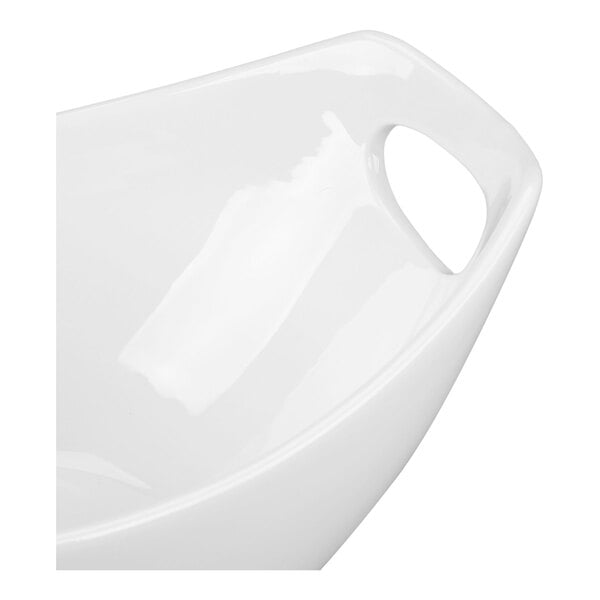 A close-up of a glossy white bowl with a built-in handle.