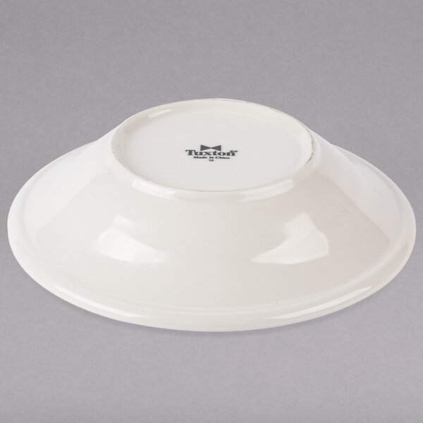 A white Tuxton Hampshire soup bowl with an embossed black rim on a gray surface.