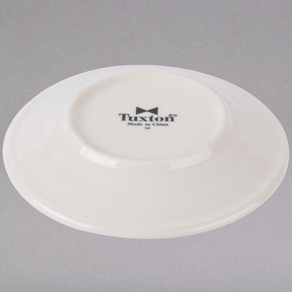A white Tuxton China bread and butter plate with embossed black text.