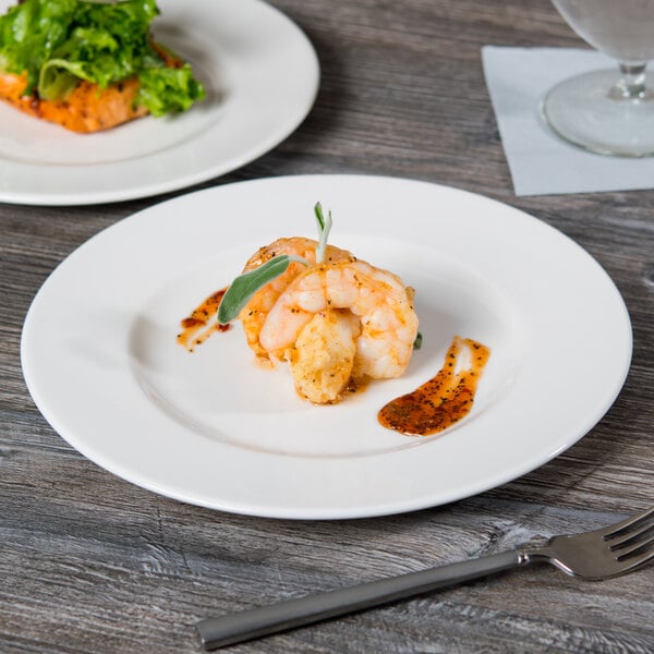 A Libbey round white porcelain plate with shrimp and a fork on it.