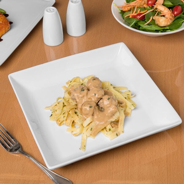 A Libbey white porcelain coupe plate with pasta and salad on it.