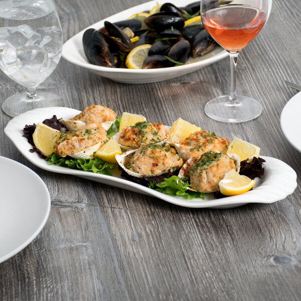 A Libbey white porcelain tray with mussels and lemons on a table.