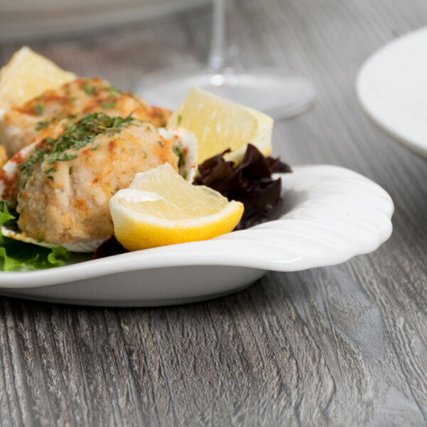 A white porcelain Libbey tray with crab cakes and a lemon wedge.