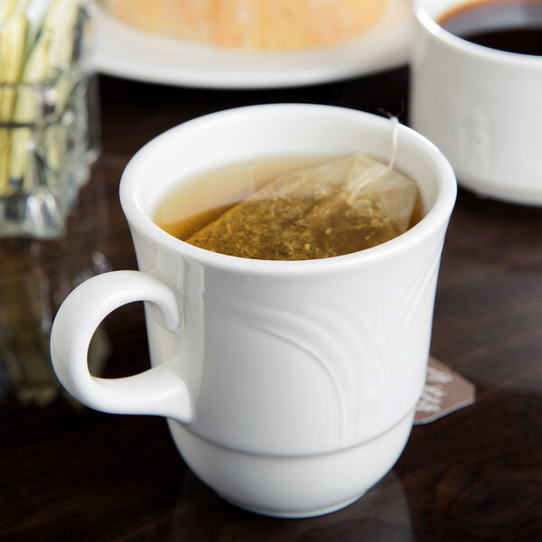 A white Reserve by Libbey tall porcelain tea cup filled with tea sits on a table.