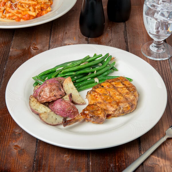 A plate of food with a fork and knife on a white porcelain plate.