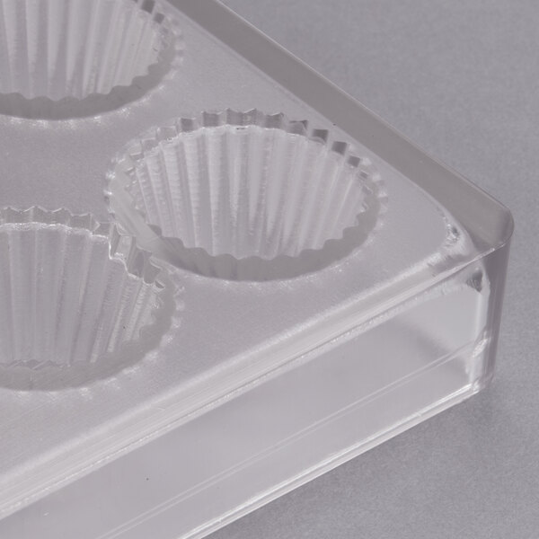 A clear plastic Chocolate World mold with 24 cup compartments.