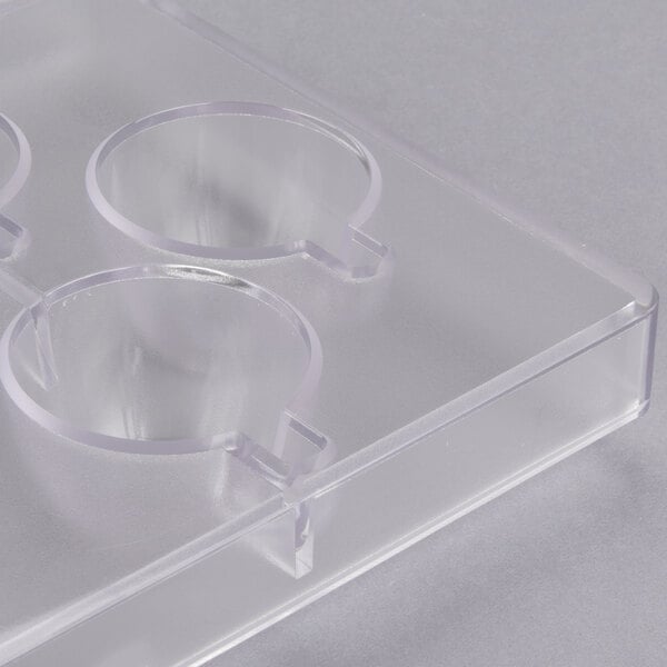 A clear plastic container with seven espresso cup-shaped holes.