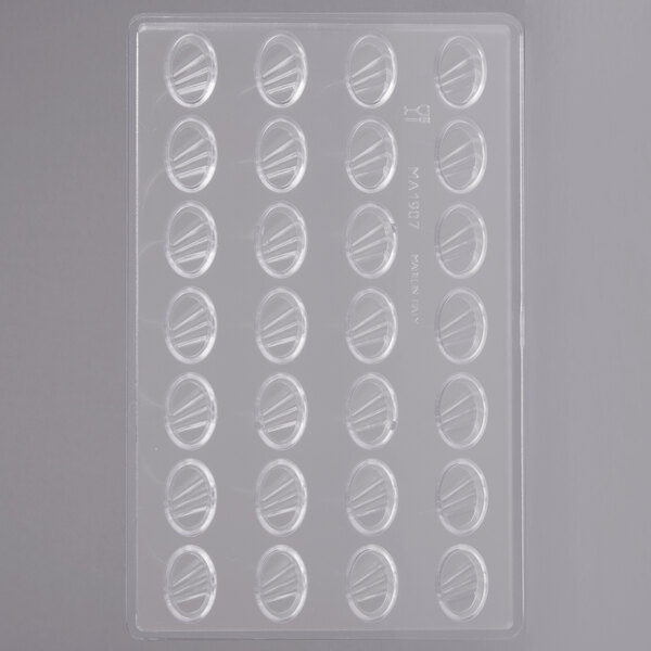 A white plastic Martellato candy mold tray with oval compartments with ribbed lines in it.