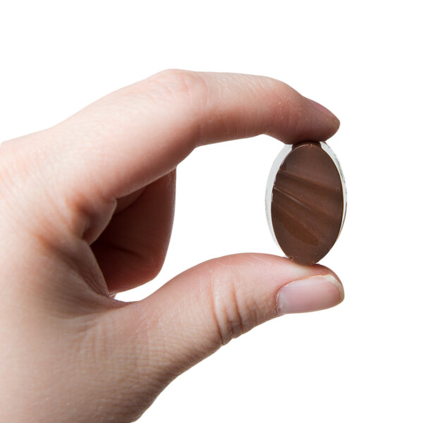 A hand holding a chocolate candy made with a Martellato ribbed oval chocolate mold.