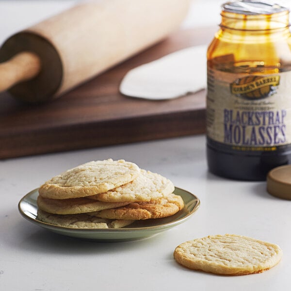 A plate of cookies and a jar of Golden Barrel blackstrap molasses on a table.