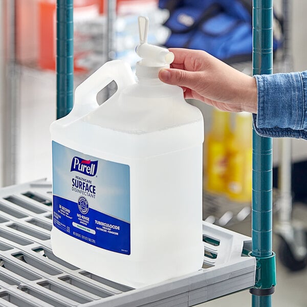 A hand holding a gallon container of Purell Fragrance Free Healthcare Surface Disinfectant.