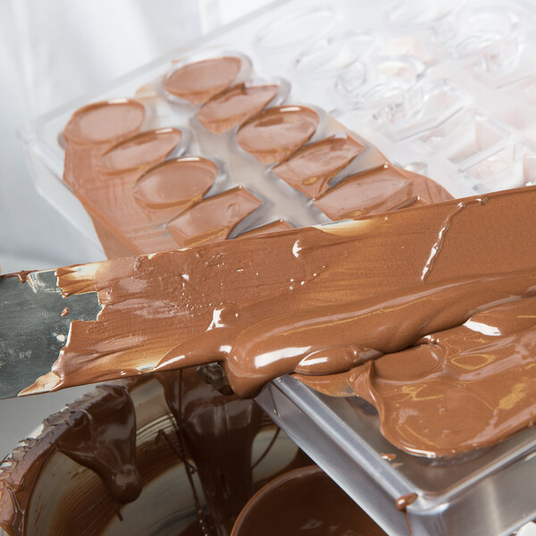 Melted chocolate being poured into a chocolate mold.