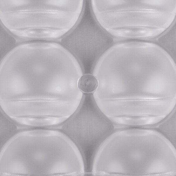 A close-up of a clear plastic Matfer Bourgeat chocolate mold with half circle compartments.