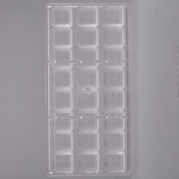 A clear plastic Chocolate World square mold with small square compartments.