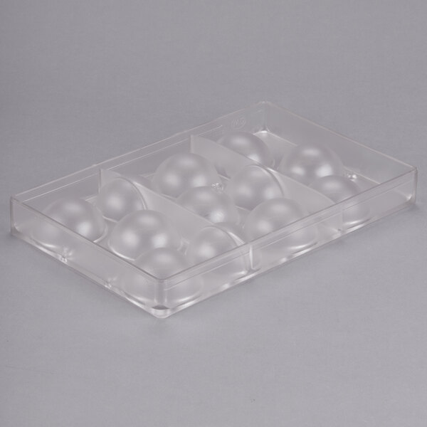A clear plastic container with round balls on a white surface.