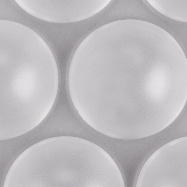 A close-up of a white polycarbonate half sphere chocolate mold.