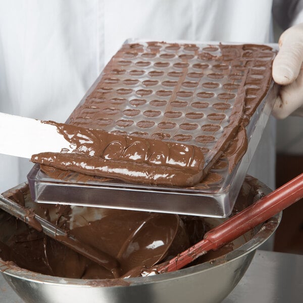 A person using a spatula to spread chocolate in a bowl.
