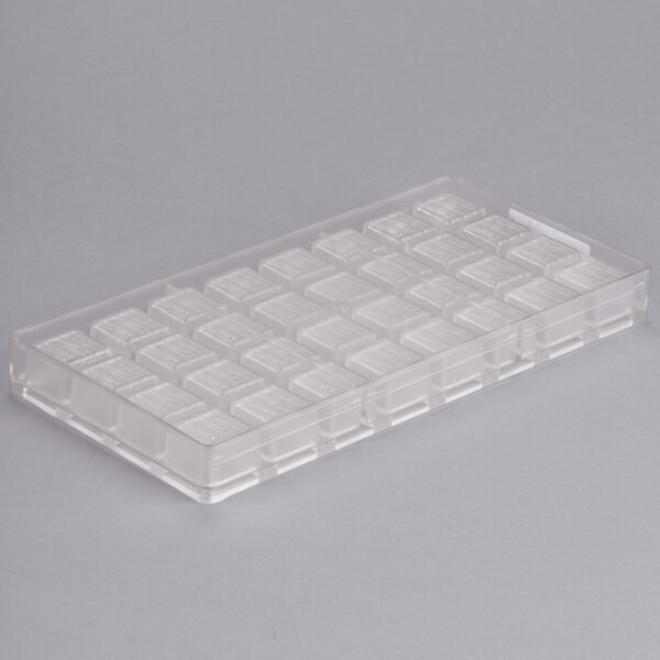 A clear plastic Chocolate World square mold tray with 32 squares.