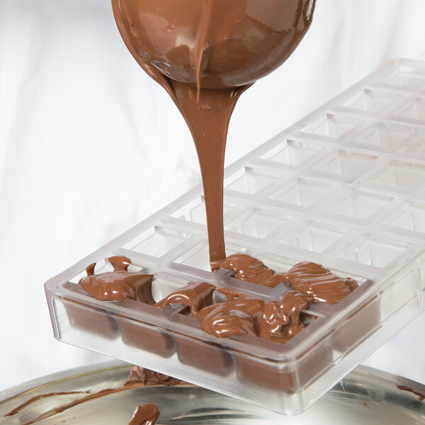 Chocolate being poured into a Chocolate World square candy mold.