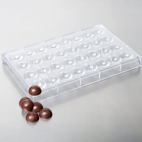 A clear plastic Matfer Bourgeat tray with round chocolate balls.