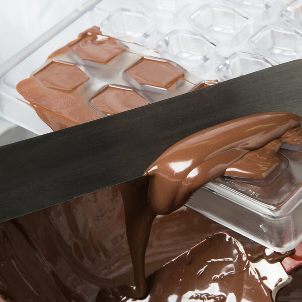 Matfer Bourgeat 36 compartment tulip rectangle chocolate mold being filled with liquid chocolate.