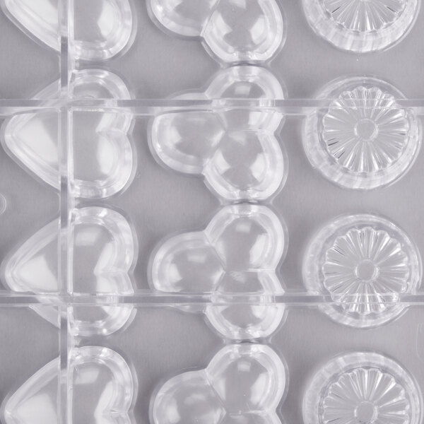 A clear plastic Matfer Bourgeat chocolate mold tray with hexagon and heart shaped compartments.