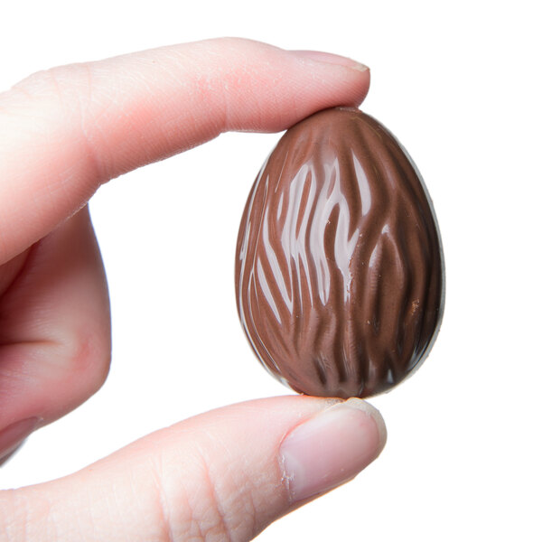 A hand holding a Matfer Bourgeat chocolate egg with a swirl pattern.