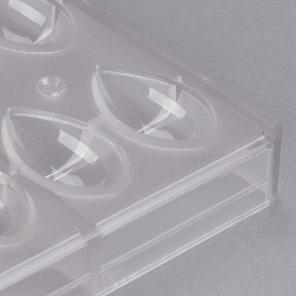 A clear plastic Chocolate World quenelle mold with teardrop-shaped compartments.