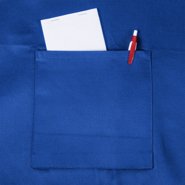 A royal blue Chef Revival bib apron with a pocket holding a pen and paper.