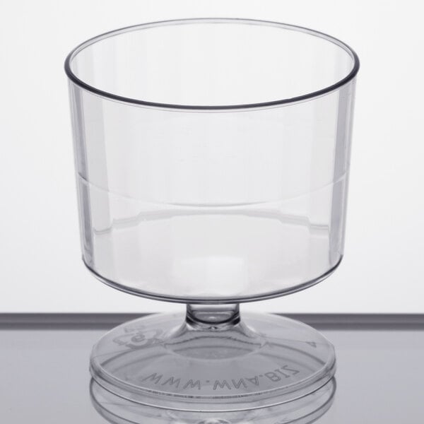 A clear plastic pedestal wine cup on a white surface.