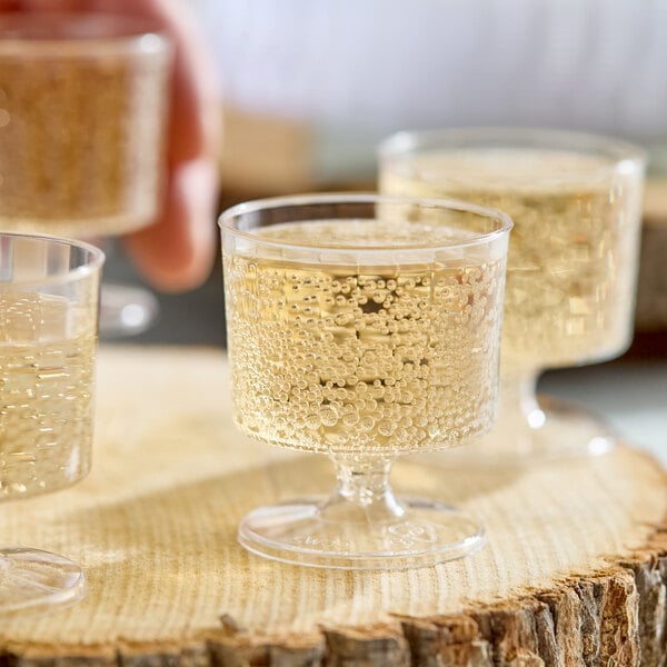 A clear plastic pedestal wine cup filled with a sparkling beverage.