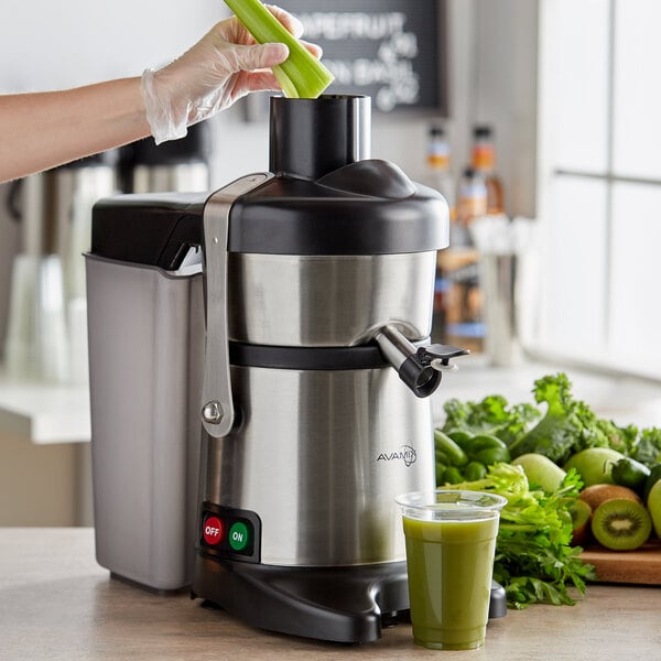 Worker juicing celery with a centrifugal juicer