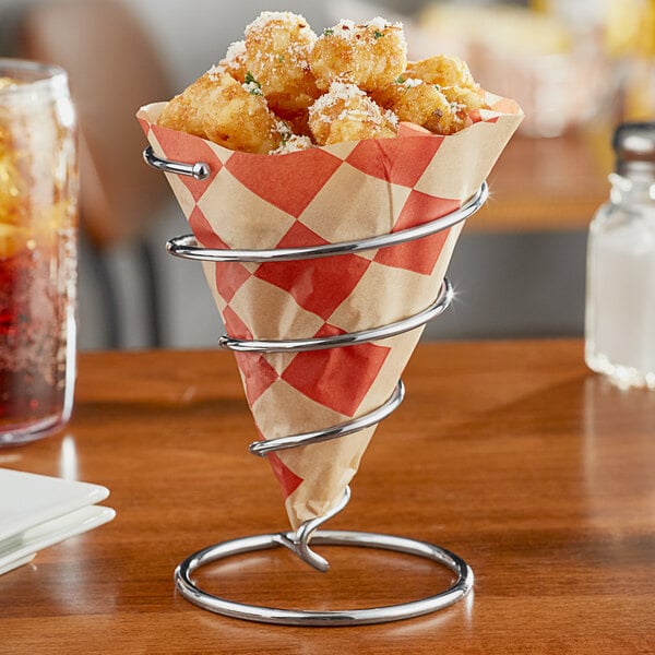 A Clipper Mill spiral metal cone basket filled with fries on a table.