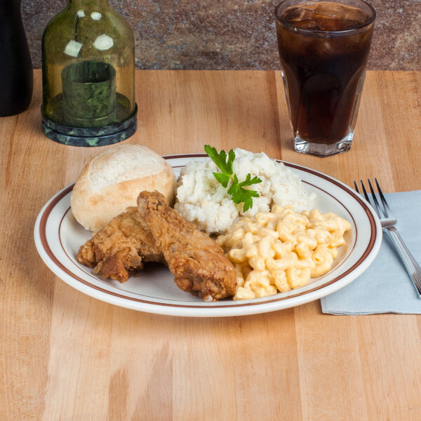 A table set with a Brown Speckle narrow rim china plate of fried chicken, mashed potatoes, and a roll.