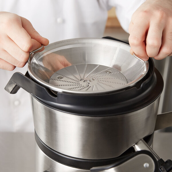 An AvaMix filter basket assembly being used to sift through food in a large metal container.