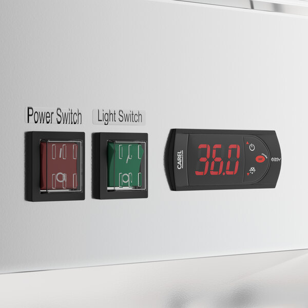 A white commercial glass door merchandiser refrigerator control panel with labeled power and light switches and a digital temperature display.