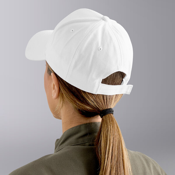 A white 6-panel baseball cap worn by a person with a ponytail.